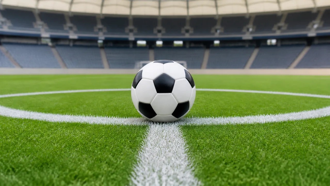 Bola de futebol posicionada no centro de um gramado